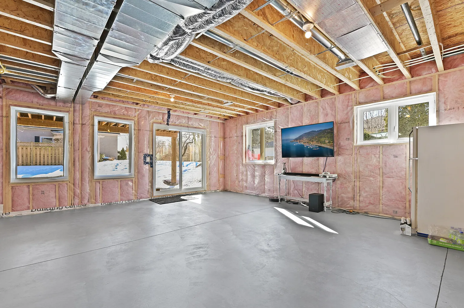 Walk-out basement in progress with framed windows and patio doors